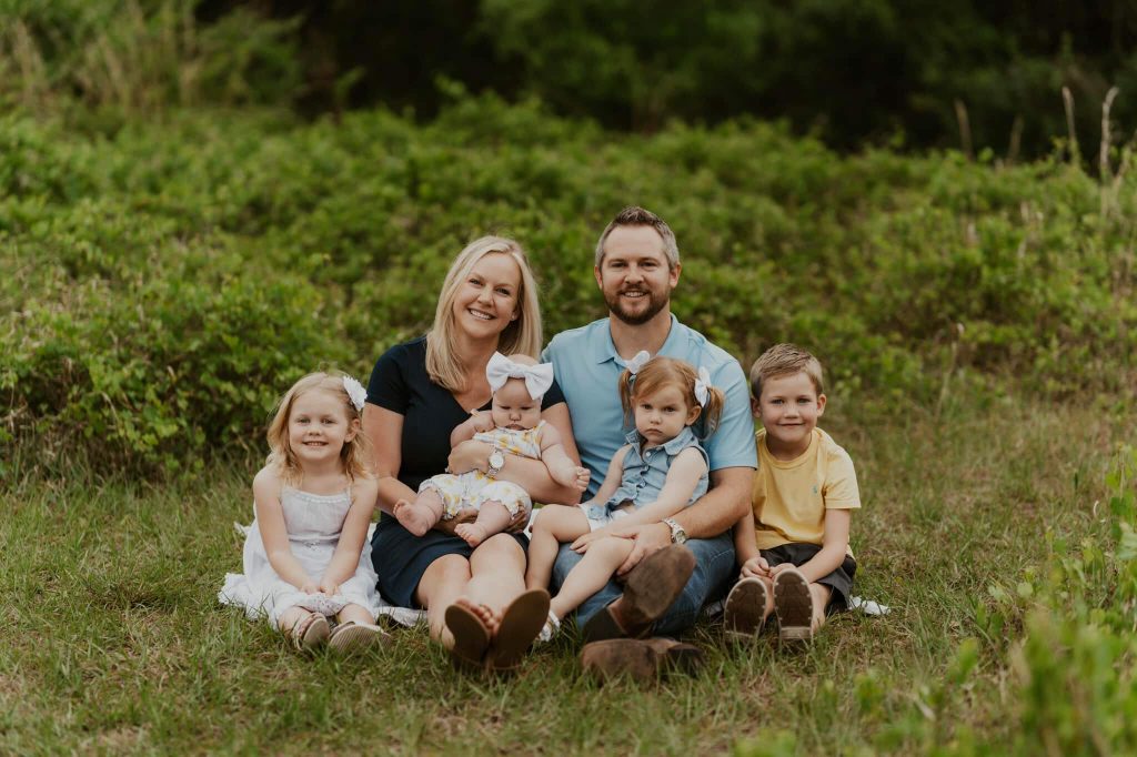Woman, man and 4 children sit on grass for family photo