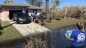 House, flooded street, people taking food toward house