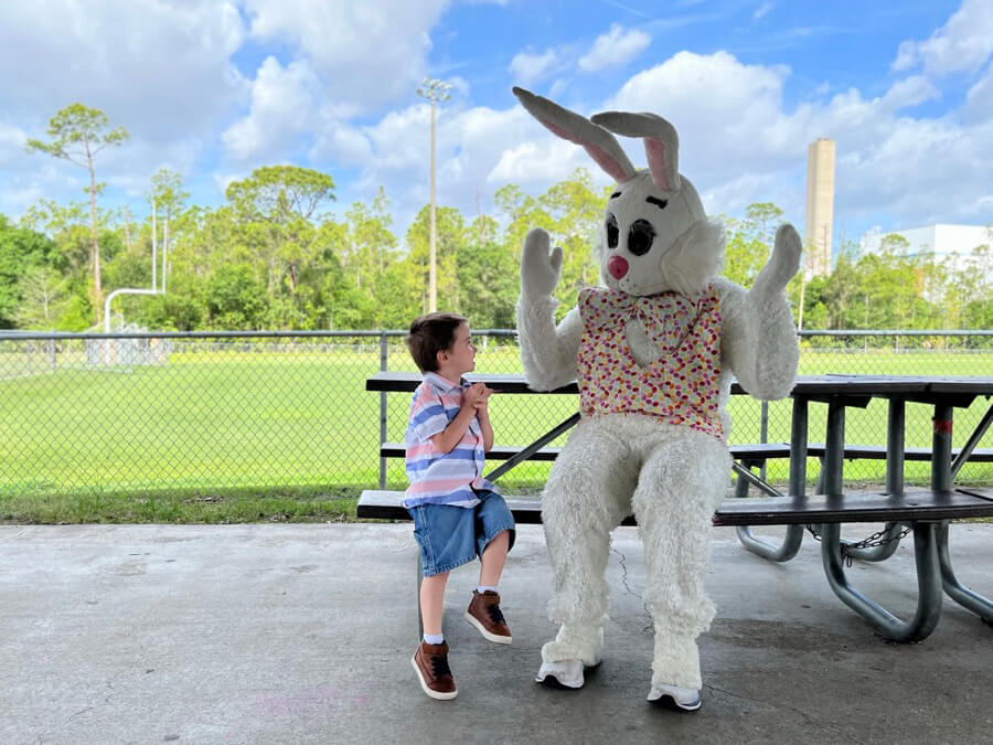Small boy excitedly approaches tall Easter bunny.