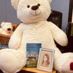 Book and photo lean against large stuffed bear
