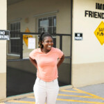 A woman stands in front of Immokalee Friendshp House smiling